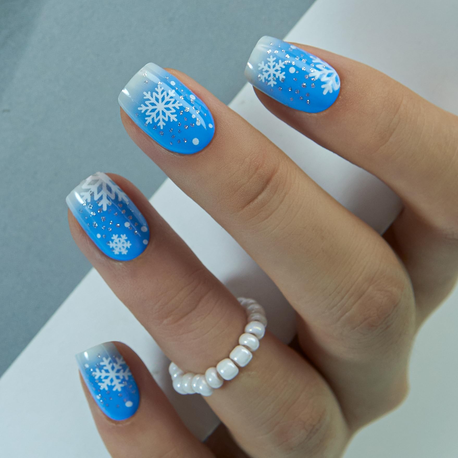 CurvLife blue ombre nails with white snowflakes for an elegant at-home manicure.