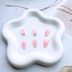 Close-up of bow and pearl designs on DAJIJIYOU nails for elegant accents