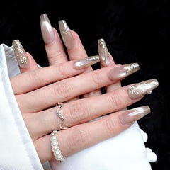 GLORS nude-base nails showcase gold leaf detail and pearl accents for refined glamour