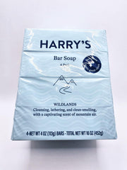 Harry's Wildlands blue bars resting on wood for rugged outdoor cleansing.