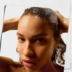 Applying Kiehl's Amino Acid Conditioner on wet hair for even coverage.