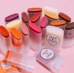 OLIO E OSSO apricot balm swatch on cheek showing coral-pink tint