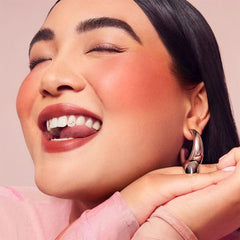 Rare Beauty Enliven mini luminizer close-up, peach with gold flecks for dewy luminosity.