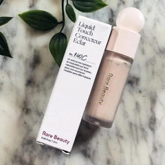 Rare Beauty Liquid Touch Brightening Concealer 140C application close-up showing creamy, blendable texture.