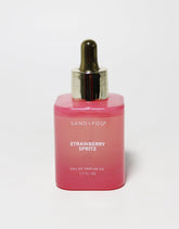 Sand + Fog Strawberry Spritz bottle on a clean surface, showcasing a vibrant, long-lasting fragrance.