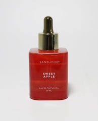 Sand + Fog Sweet Apple oil in a red bottle with a gold dropper cap for precise application