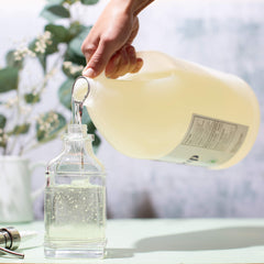 Sanit Silky Clean gallon pour closeup — simple refills with precise measurement.