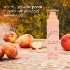 The Skylar Peach Fields bottle sits beside peaches in warm sunlight.