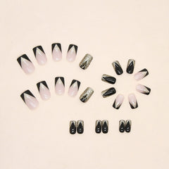 TBRZTR glossy glue-on nails: full-cover nude with black and gold accents.