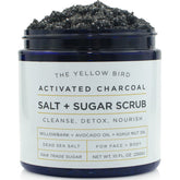 The Yellow Bird charcoal scrub jar closeup highlights rich exfoliant texture for smooth skin.
