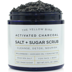 The Yellow Bird charcoal scrub jar closeup highlights rich exfoliant texture for smooth skin.