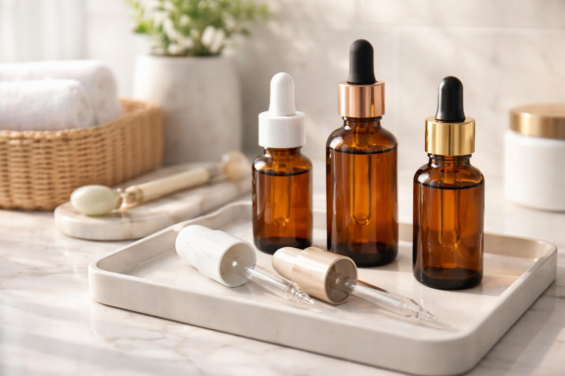 Refillable cosmetic droppers beside amber serum bottles