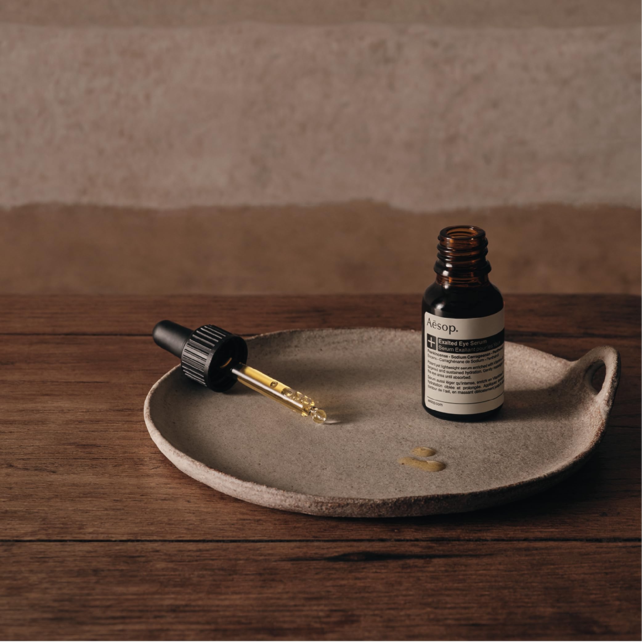 Drops dispense from Aesop Exalted Eye Serum onto the skin