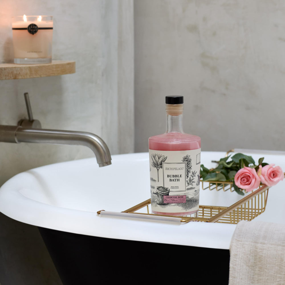 Archipelago Botanicals Charcoal Rose Bubble Bath bottle with roses and spa towels.