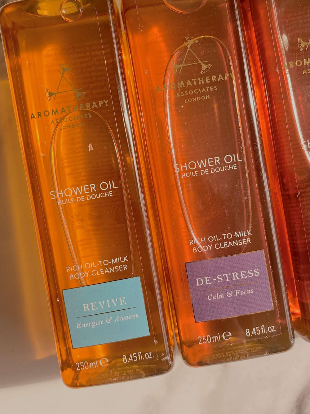 Aromatherapy Associates De-Stress Muscle Shower Oil bottle with warm golden hue.