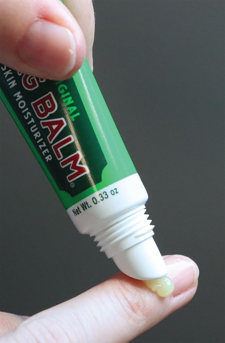 Hands applying Bag Balm to dry skin for quick relief.