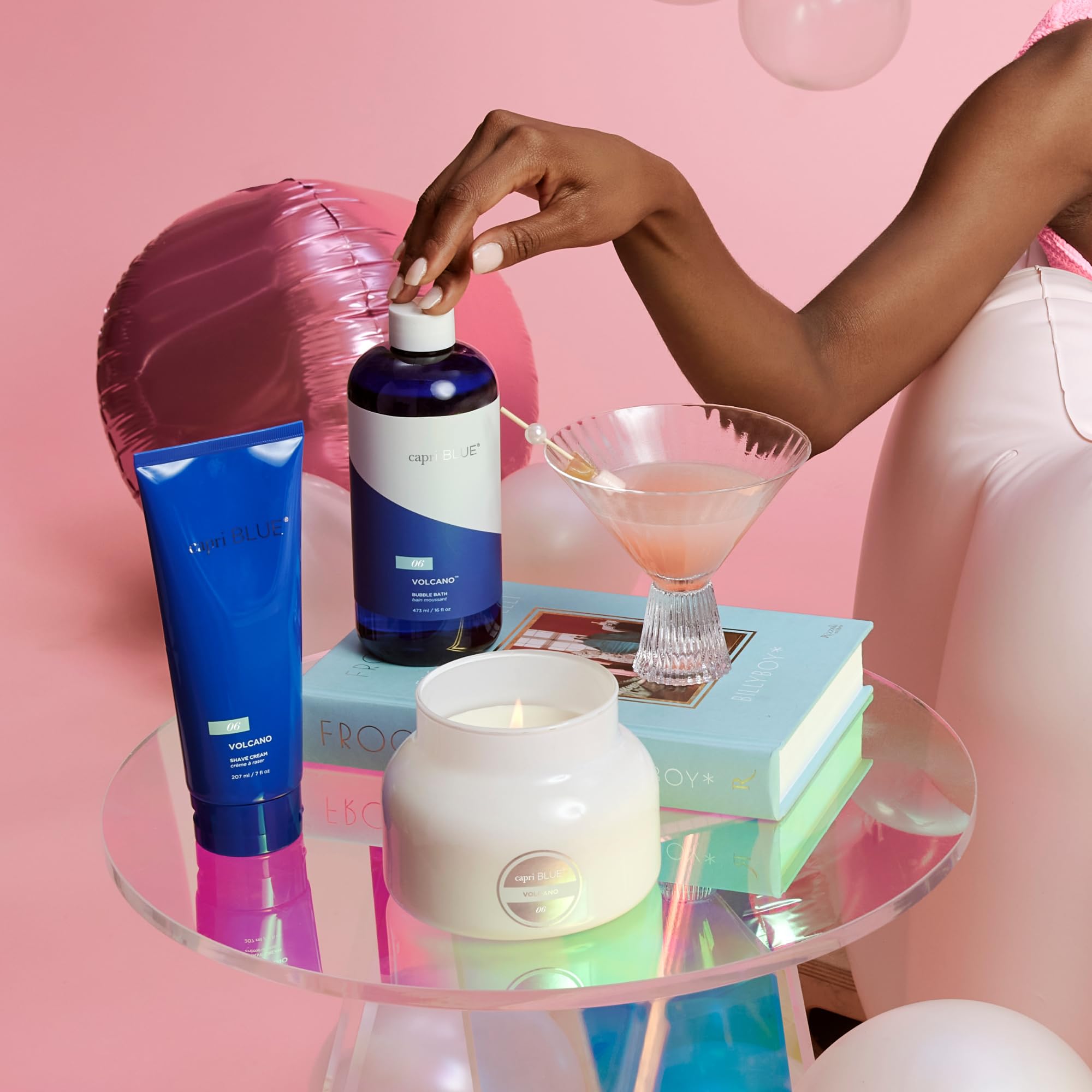 Capri Blue Volcano Bubble Bath scene with candle and book sets mood for relaxation.