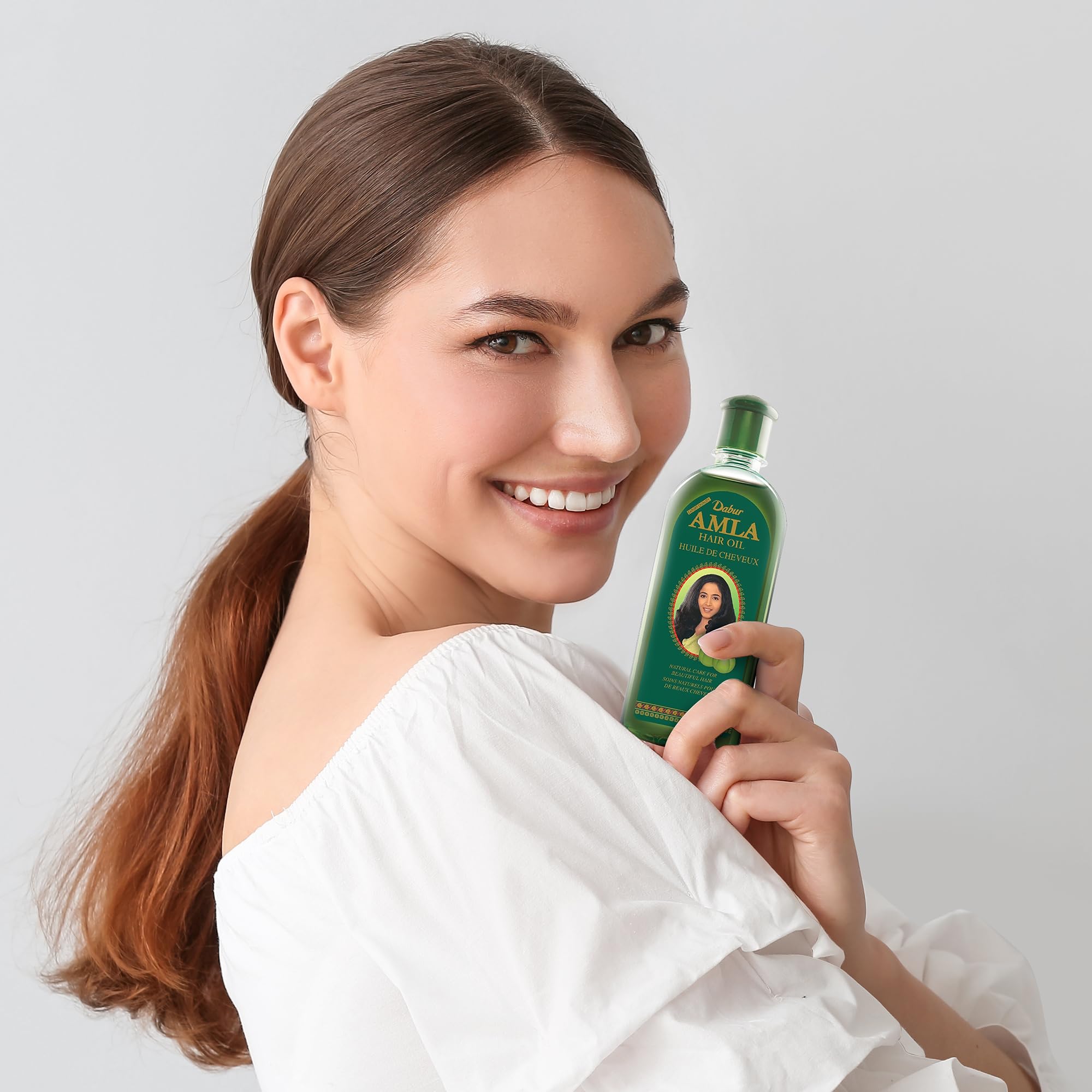 Dabur Amla Hair Oil in-use hand applying oil to scalp for nourishment.
