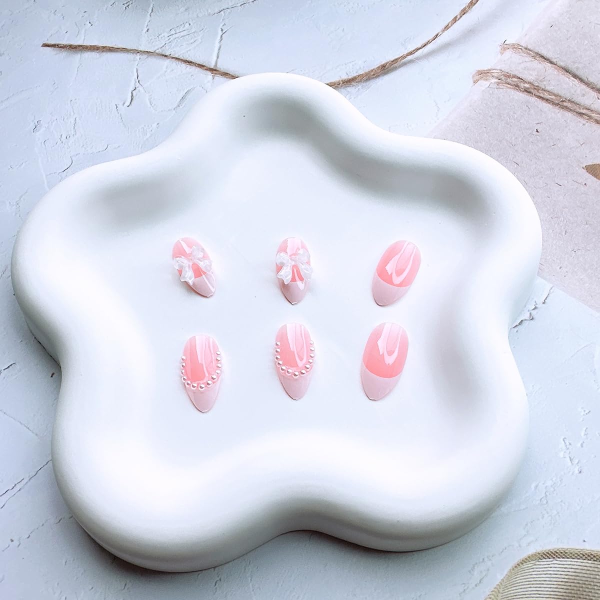 Close-up of bow and pearl designs on DAJIJIYOU nails for elegant accents