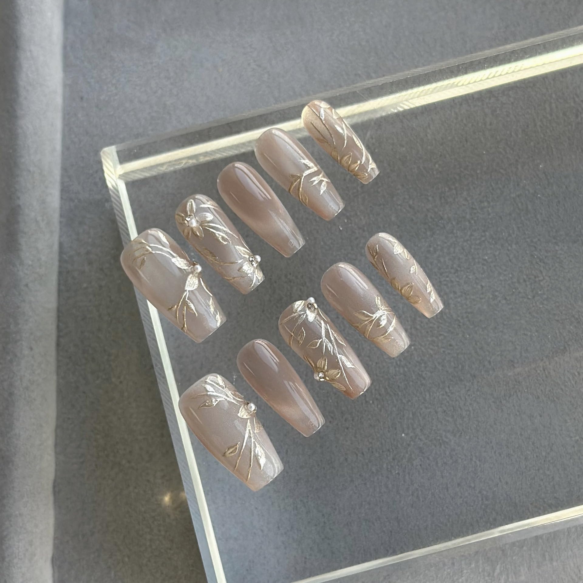 Long ballerina GLORS nails catching light with metallic gold design