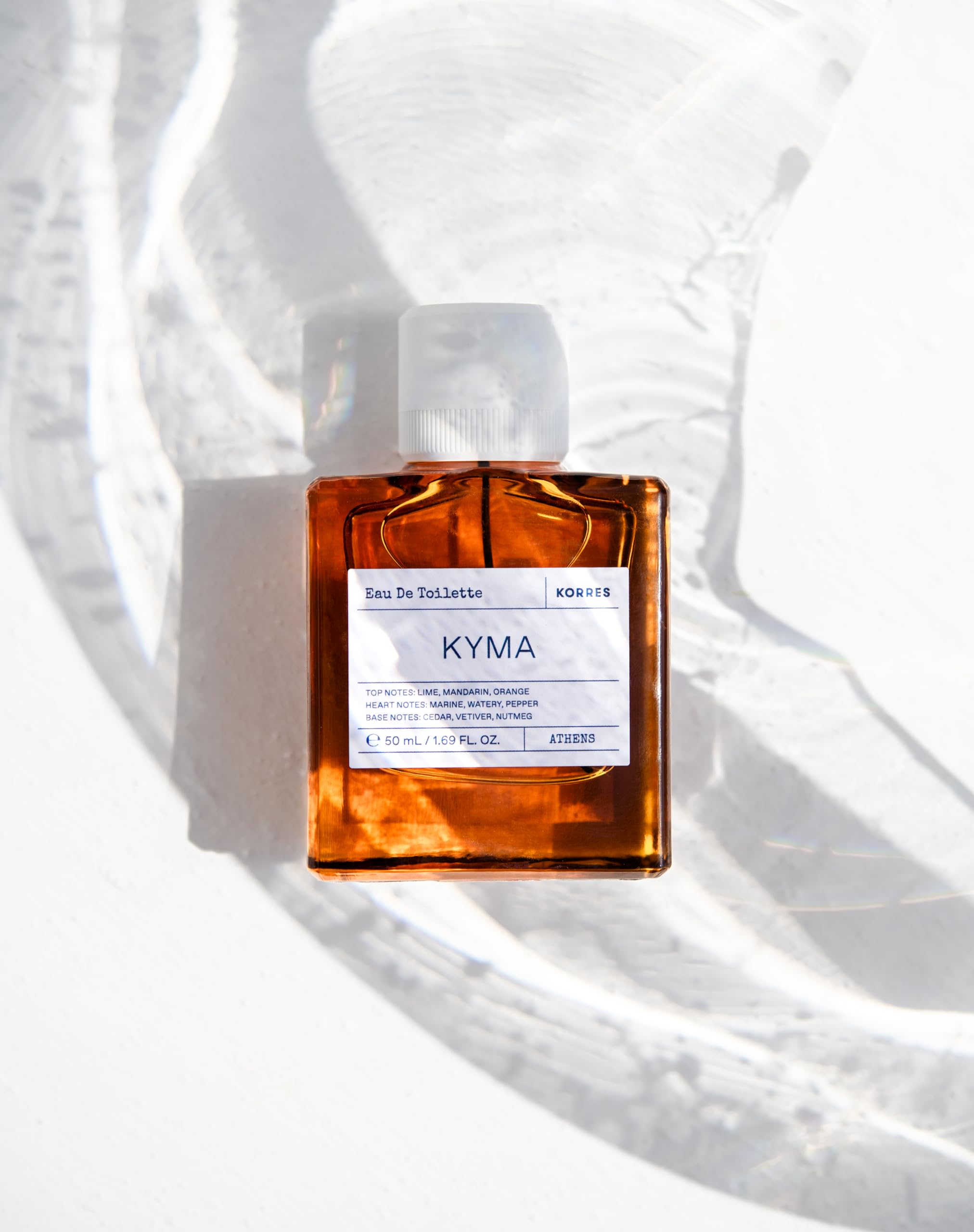 Korres Kyma base-notes close-up with cedar and vetiver for a warm finish.