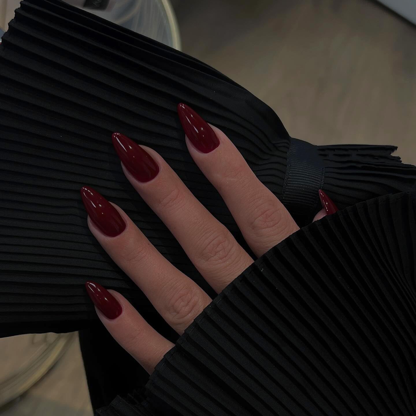 KQueenest burgundy nails on finger highlighting glossy stiletto shape