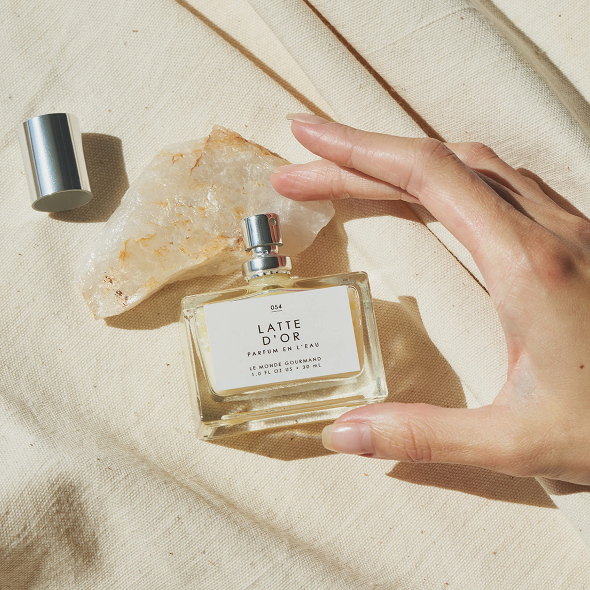 Bottle on wooden surface evokes creamy sandalwood warmth and coconut tones.