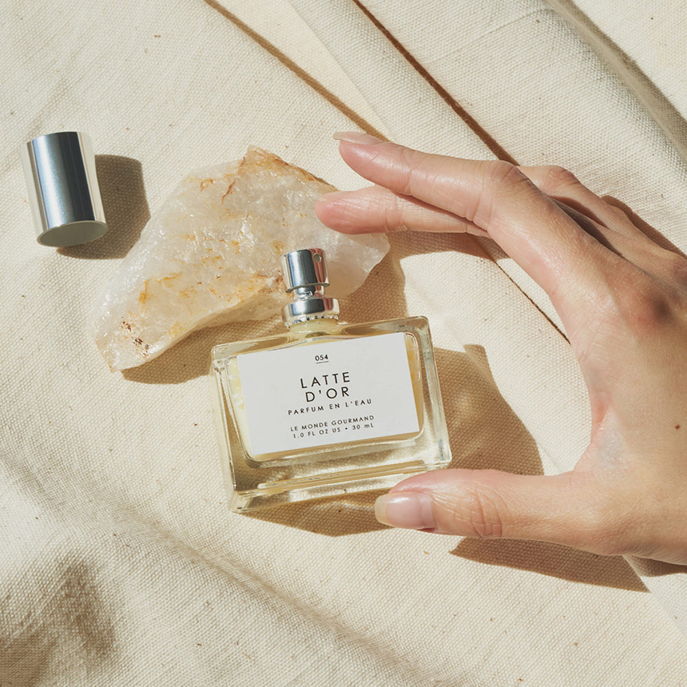 Bottle on wooden surface evokes creamy sandalwood warmth and coconut tones.