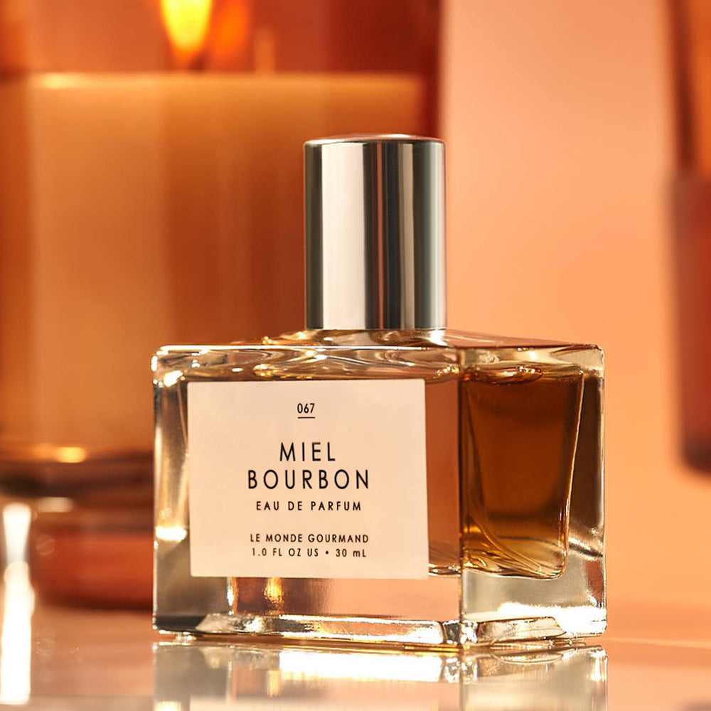 Le Monde Gourmand Miel Bourbon EDP glass bottle glows in warm light.