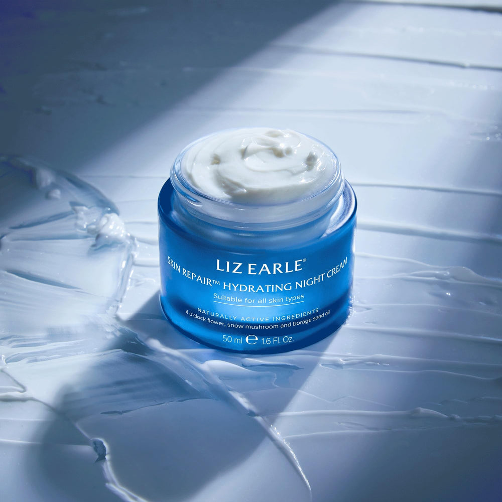 Liz Earle Skin Repair Night Cream bottle on vanity with soft lighting.