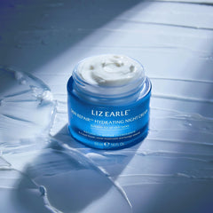 Liz Earle Skin Repair Night Cream bottle on vanity with soft lighting.