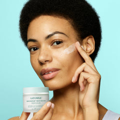 Liz Earle Skin Repair Rich Cream bottle on desk suggests premium care.