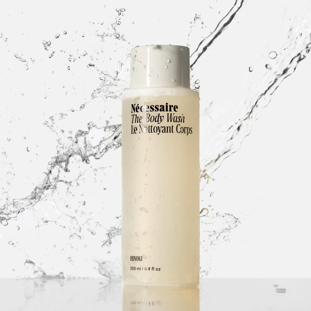 Nécessaire Hinoki body wash splash in the shower illustrates rich fragrance notes.