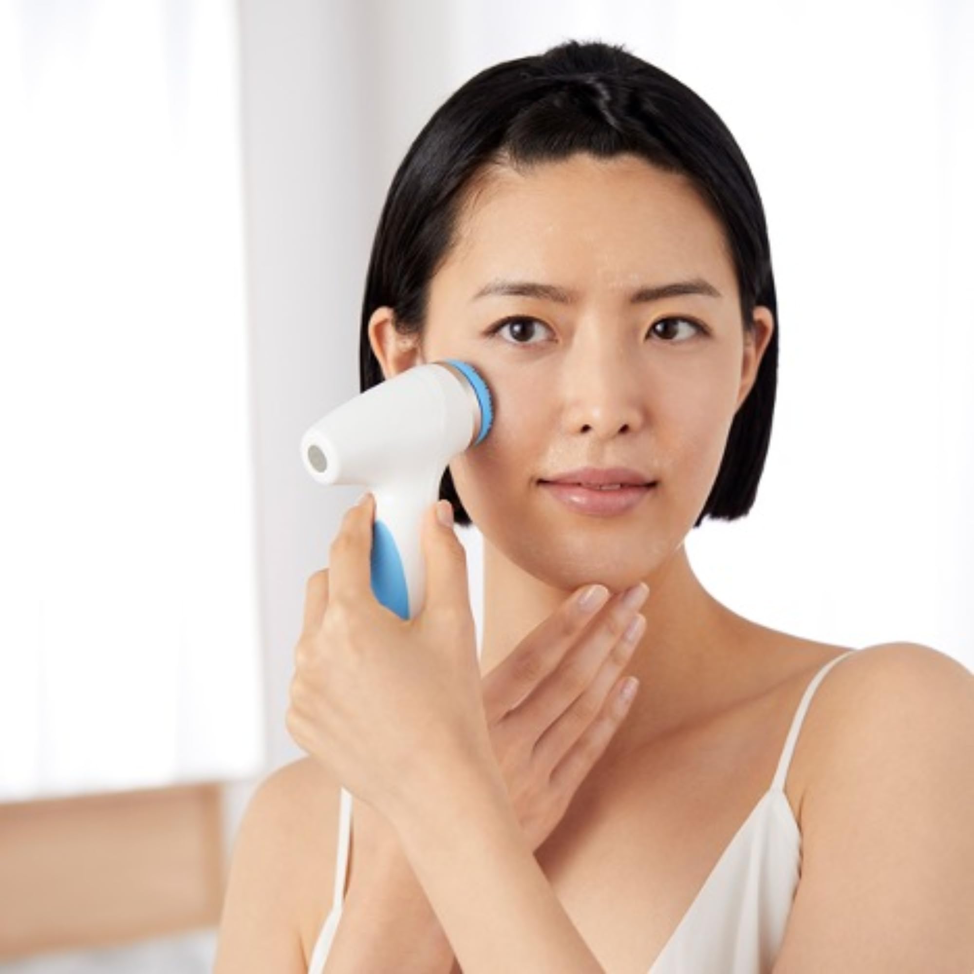 Hands holding Nu Skin ageLOC LumiSpa cleanser bottle during skincare routine.