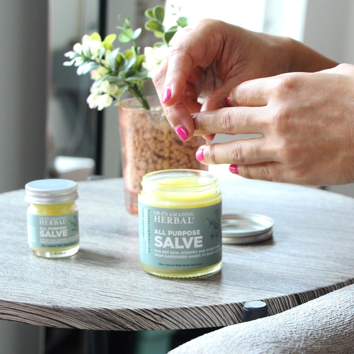 Hands applying Ora's Amazing Herbal Salve for quick daily relief.