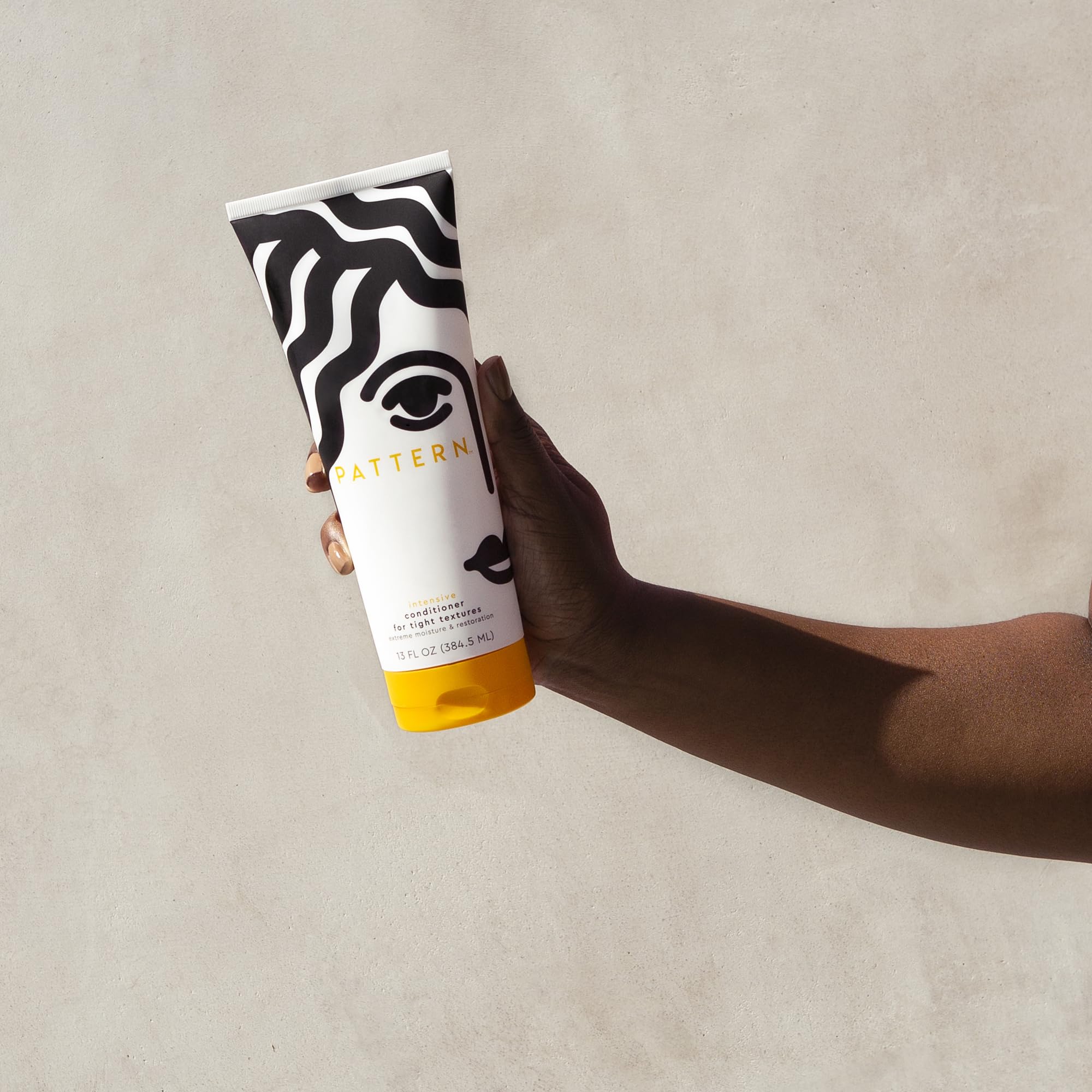 PATTERN Beauty Intensive Conditioner close-up on hair strands shows thick, creamy consistency.