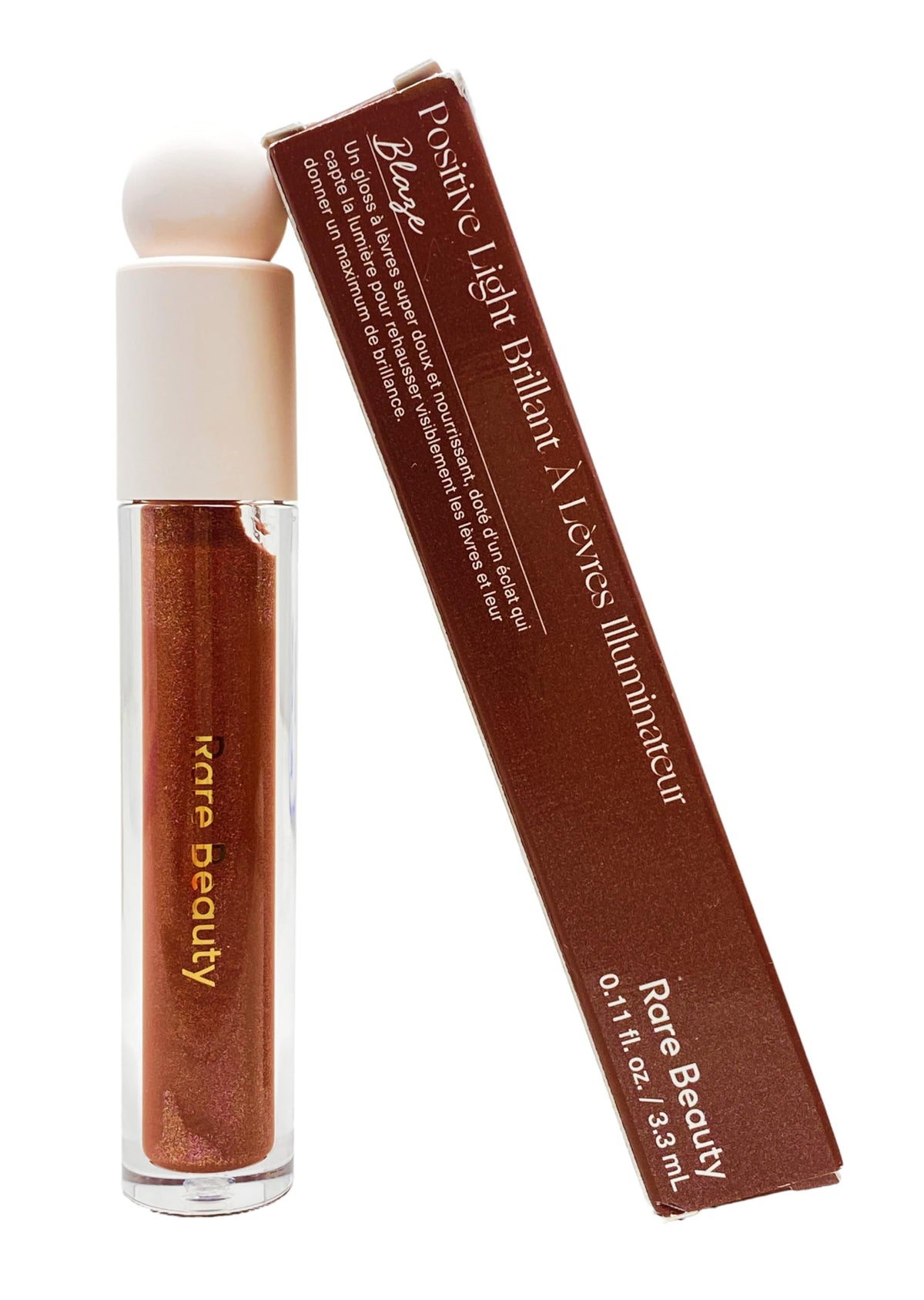 Rare Beauty Blaze luminizing gloss bottle with maroon-gold shimmer for radiant lips.