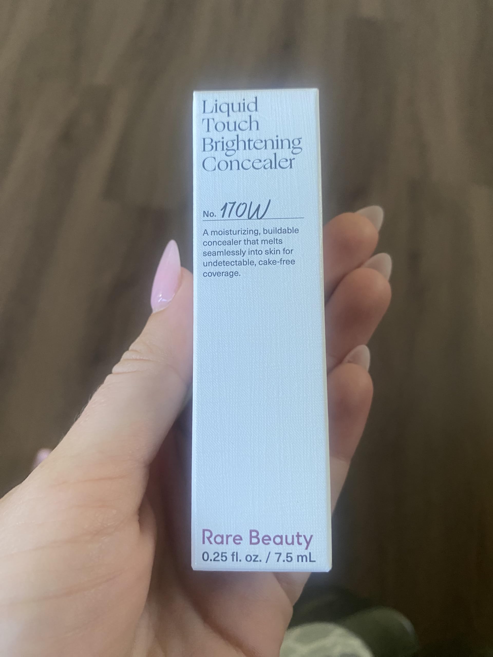 Application close-up of Rare Beauty Liquid Touch 170W blending for bright under eyes.
