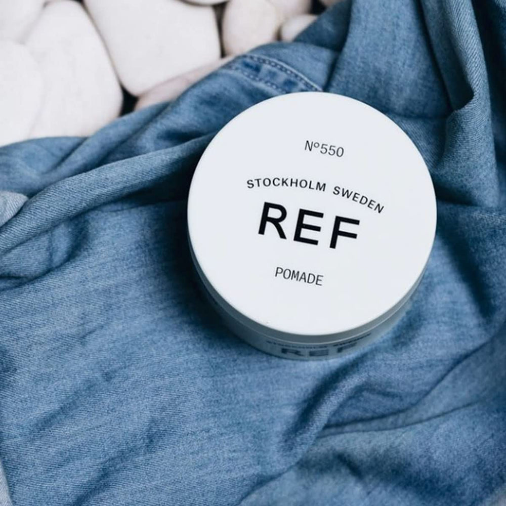 Hands applying REF Pomade N 550 for easy styling.