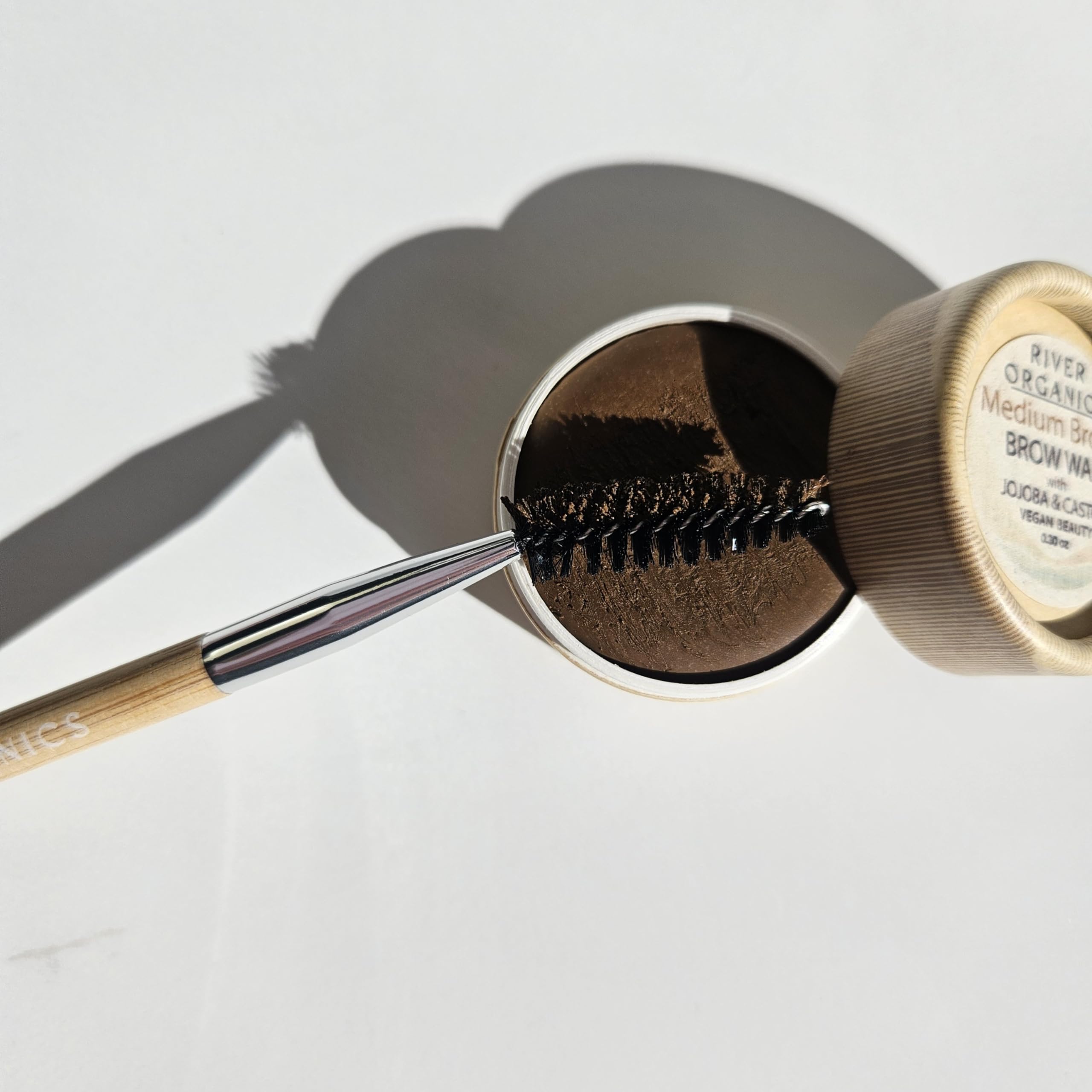 River Organics Chestnut Brow Wax in use with bamboo wand for defined brows.