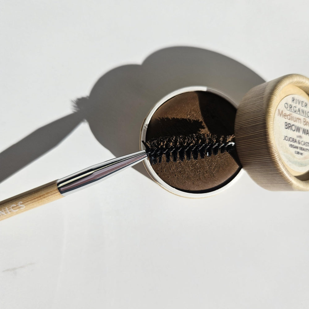 River Organics Chestnut Brow Wax in use with bamboo wand for defined brows.