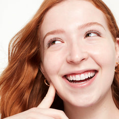 Application on fingertip shows Saie Glowy Super Skin Tint coverage.