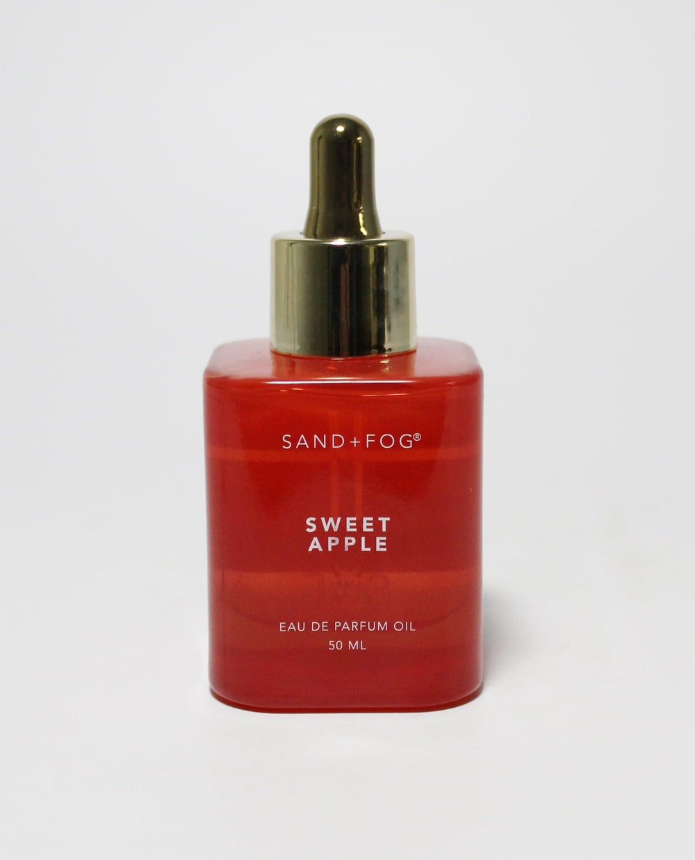 Sand + Fog Sweet Apple oil in a red bottle with a gold dropper cap for precise application