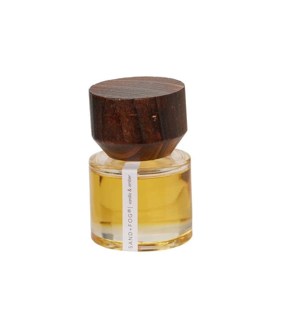 Sand + Fog Vanilla and Amber perfume oil bottle with wooden cap, for long-lasting scent on pulse points.