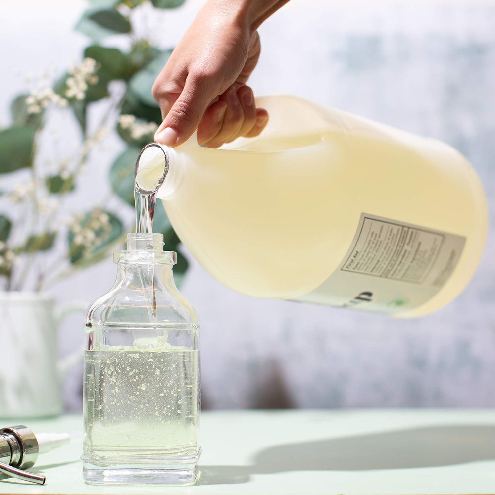 Sanit Silky Clean gallon pour closeup — simple refills with precise measurement.