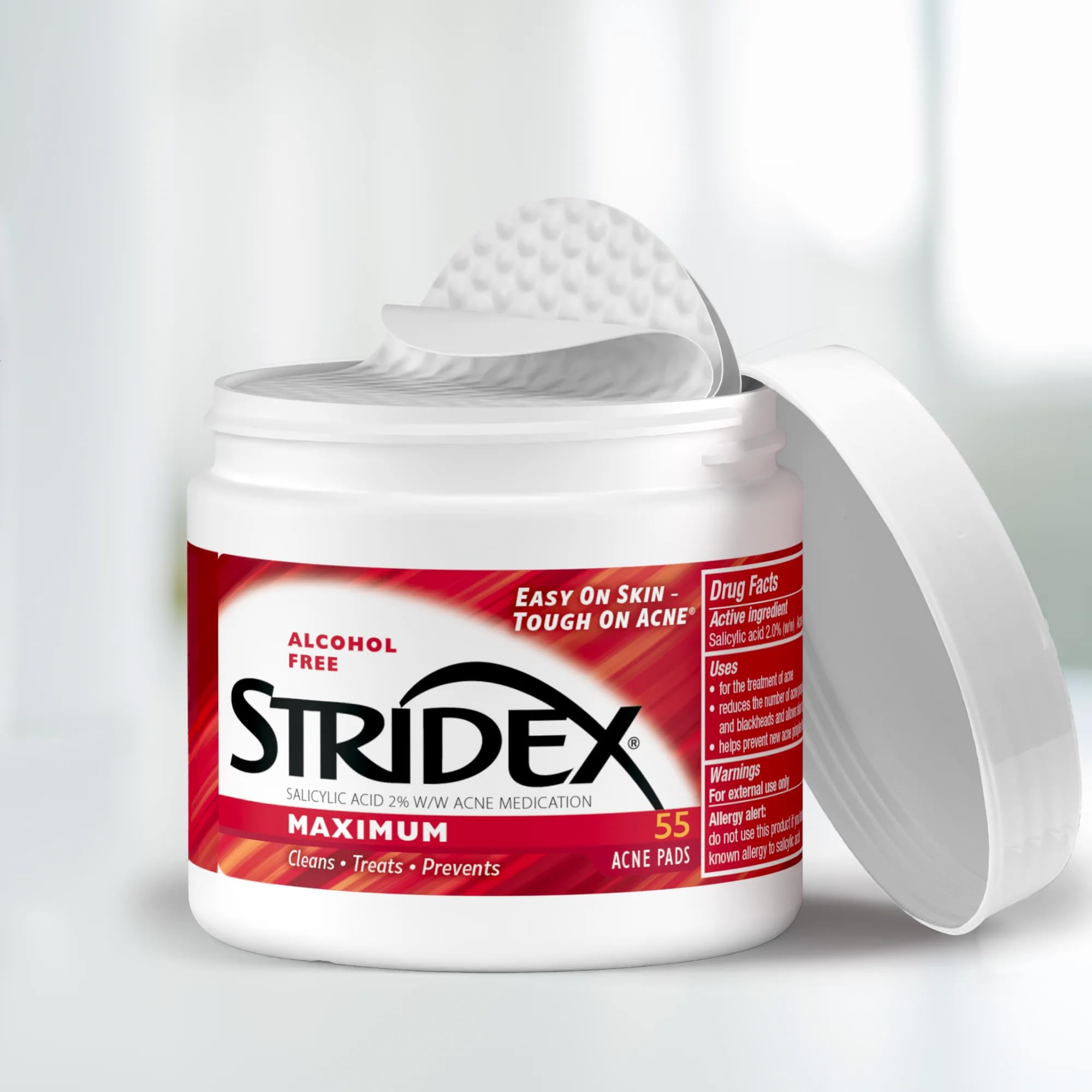 Hands applying Stridex pad to clean skin for treatment.