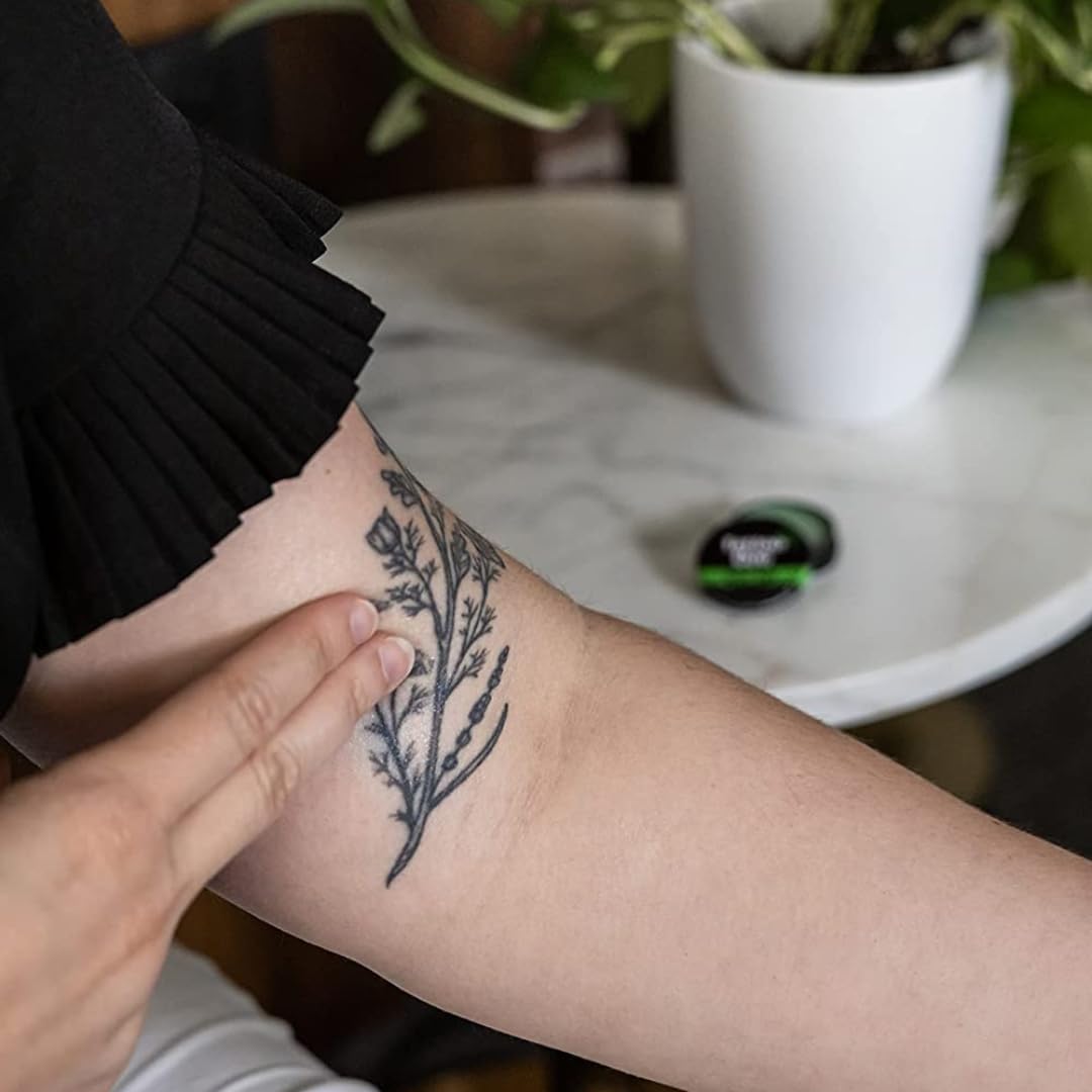 Tattoo Goo balm being applied to a fresh tattoo, supporting moisture and comfort.
