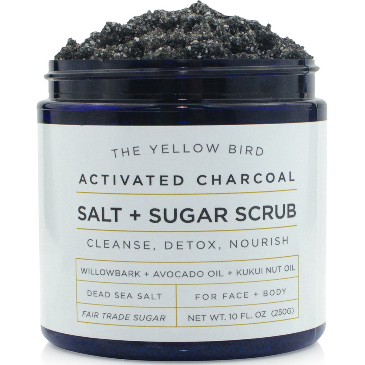 The Yellow Bird charcoal scrub jar closeup highlights rich exfoliant texture for smooth skin.