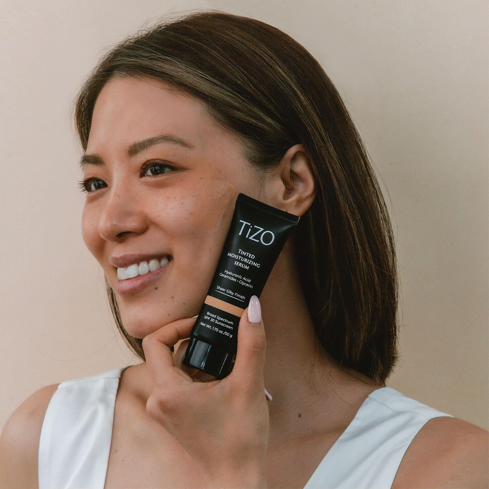 TIZO tinted moisturizing serum bottle close-up emphasizes sheer tint and skin tone enhancement.