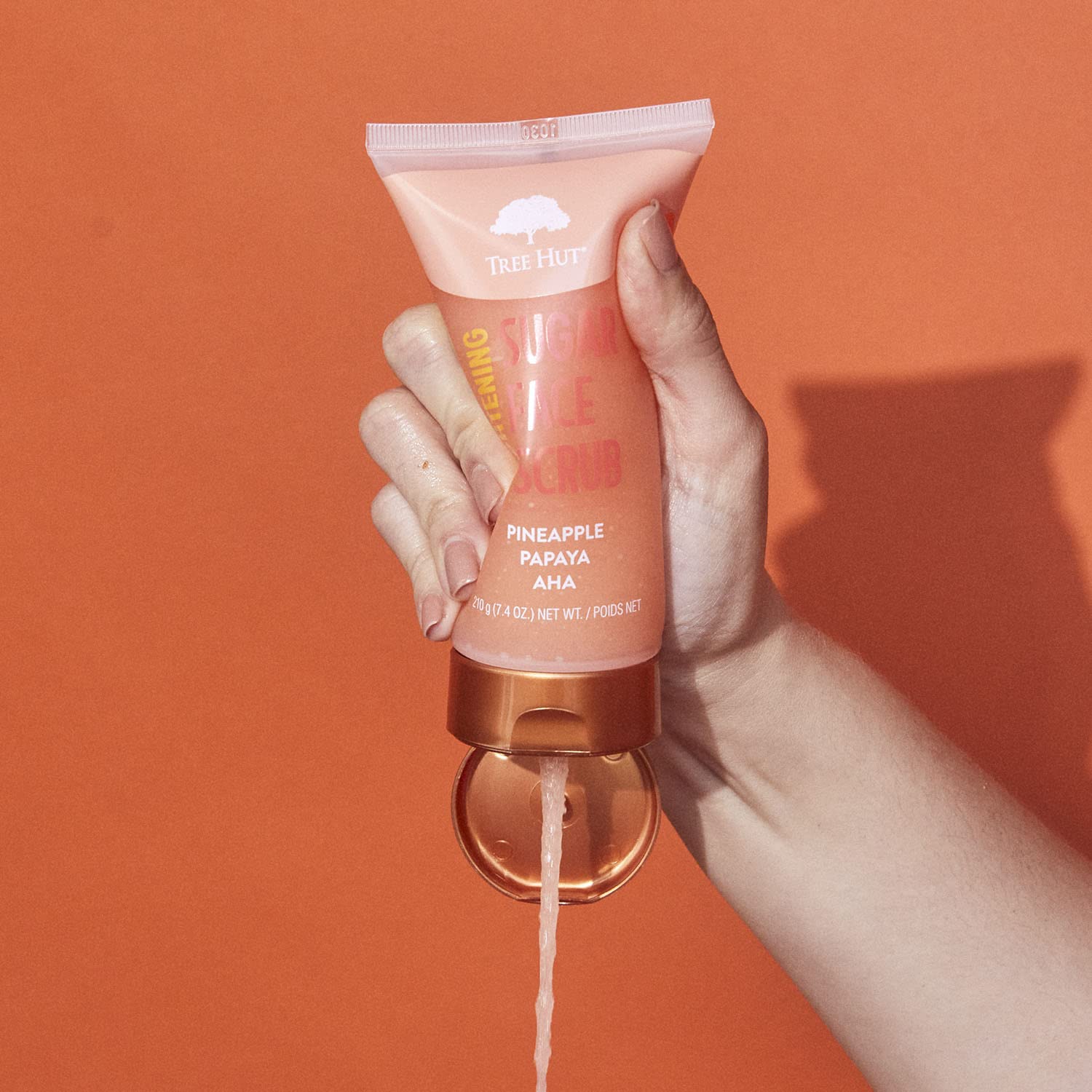 Product being poured from Tree Hut Pineapple Papaya Face Scrub for even application.